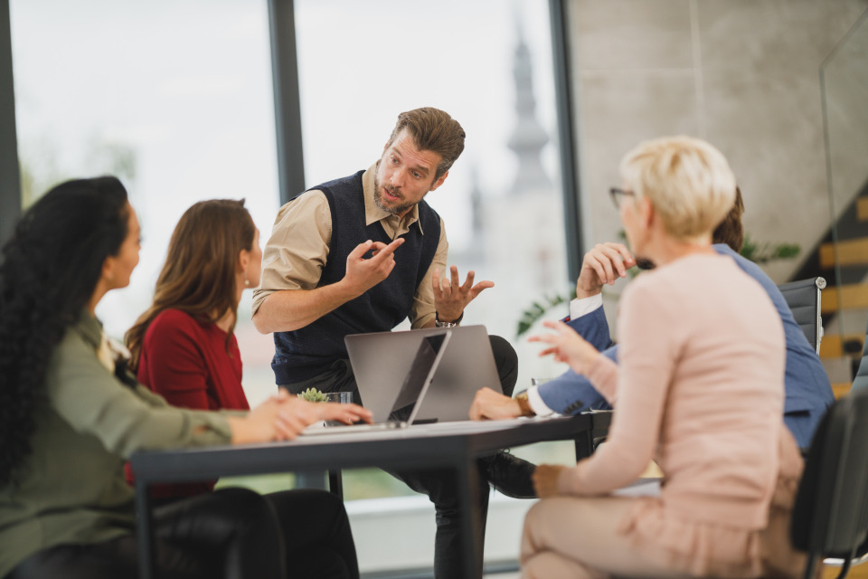 Team discussing plans around a laptop in a business meeting