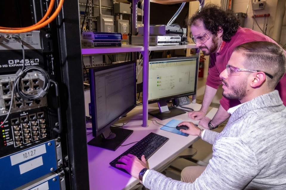 Two IT engineers reviewing systems on monitors near server racks