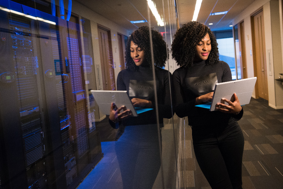 A professional reviewing a tablet in a server room corridor